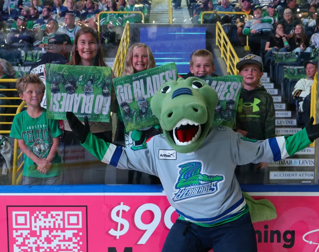 Florida Everblades mascot with young fans holding signs in a packed arena